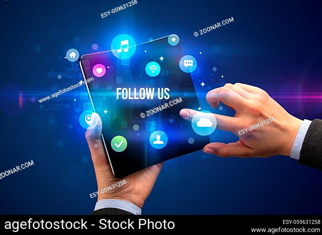 Businessman holding a foldable smartphone with FOLLOW US inscription, social media concept