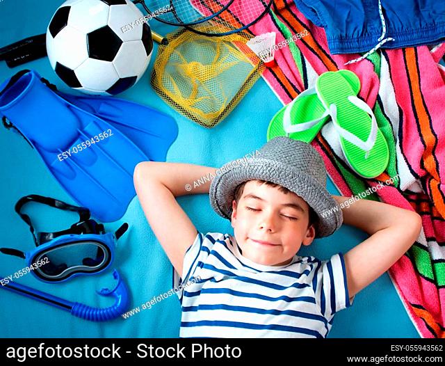 boy in straw hat with towel and toys on blue blanket