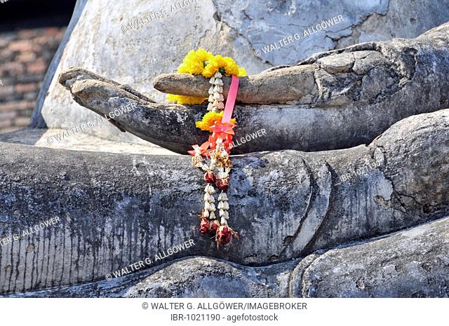 Buddha statue, Bhumispara-mudra, Gautama Buddha in the moment of enlightment, close up of a hand decorated wth flowers, Wat Sa Si, Sukhothai Historical Park
