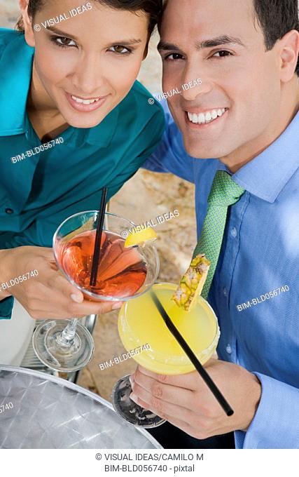 Hispanic couple toasting with cocktails