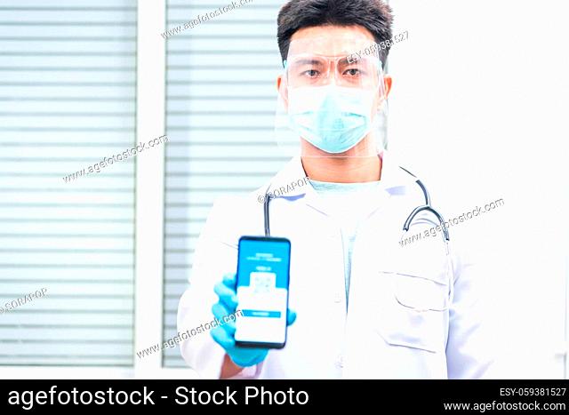 Doctor man in medical mask show app smartphone mobile digital vaccinated passport coronavirus (COVID-19) certificate to confirm, vaccine health pass concept