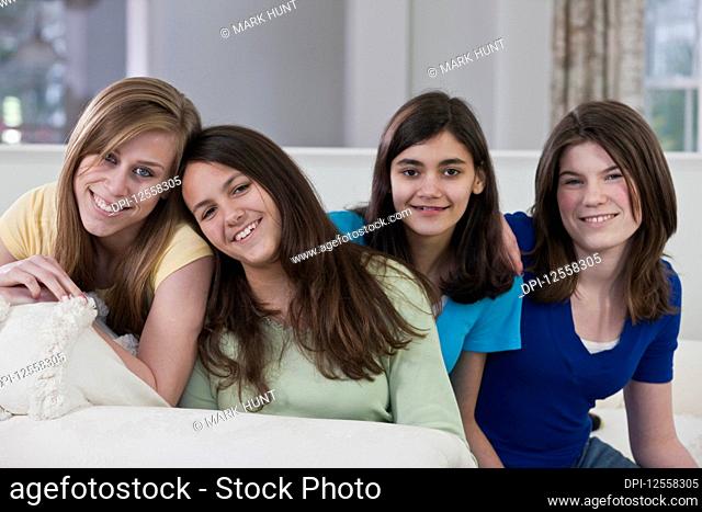 Portrait of four teenage girls sitting on a couch at home