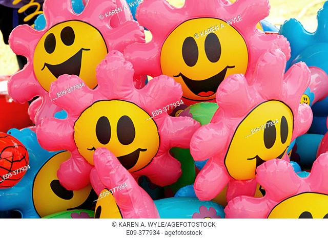 Pink and yellow flower smiley-face balloons at carnival booth at county fair, Monroe County, Indiana, USA