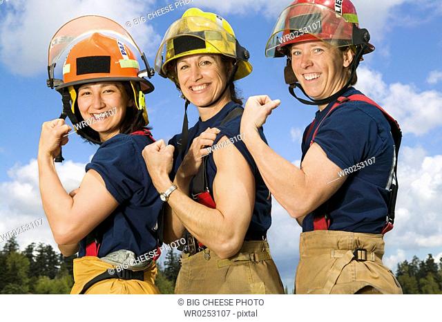 Portrait of female firefighters flexing biceps