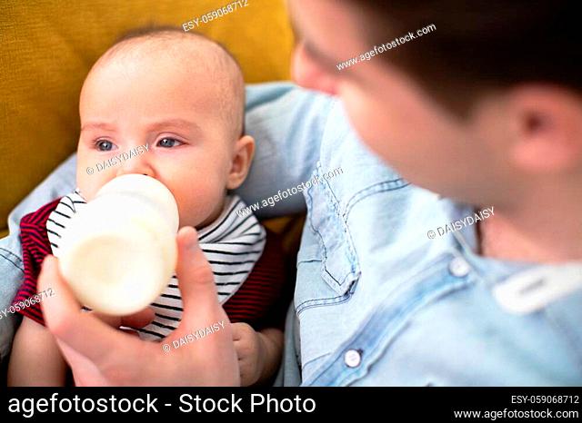 Close Up Of Loving Feeding baby Son With Bottle At Home