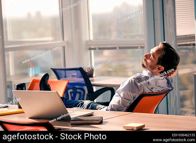 Businessman resting and relaxing after hard working day in office interior. Handsome middle aged man sleeping in chair. Business project concept