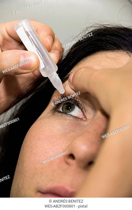 Ophthalmologist pouring eye drops in the eye of a patient