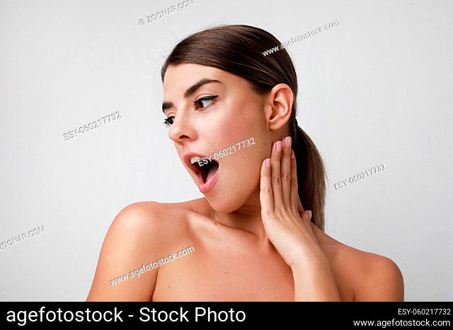 Surprised happy brunette woman and looking aside over white background. High quality photo