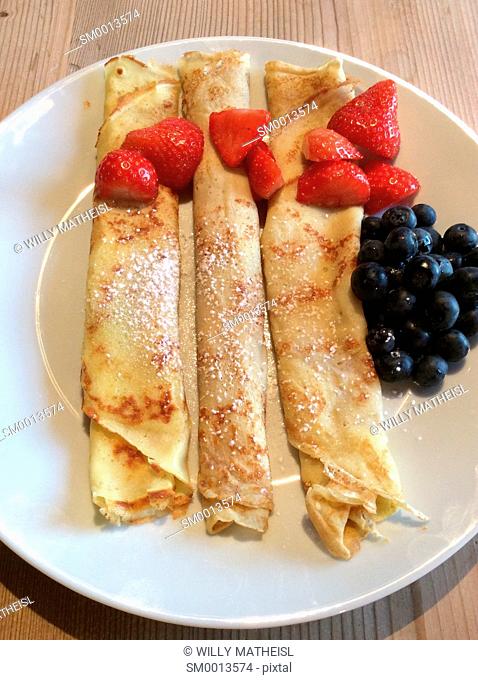 Homemade Bavarian pancakes with strawberries, sugar powder and fresh blueberries