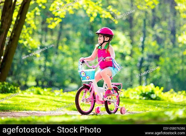 Child riding bike. Kid on bicycle in sunny park. Little girl enjoying bike ride on her way to school on warm summer day. Preschooler learning to balance on...