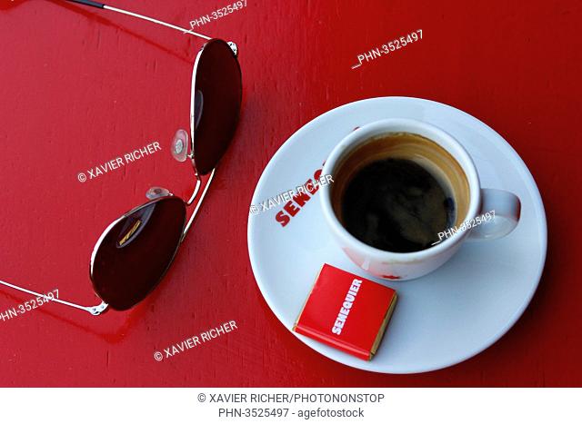 France, Var department, city of Saint-Tropez, zoom on a coffea cup, sun glasses, on a red table of the most famous restaurant called chez Senequier