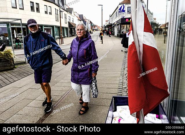Hirtshals, Denmark A pedestrian senior couple on the main street with Danish flag
