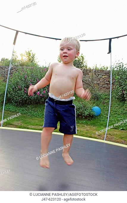 3 year old boy bouncing on a trampoline