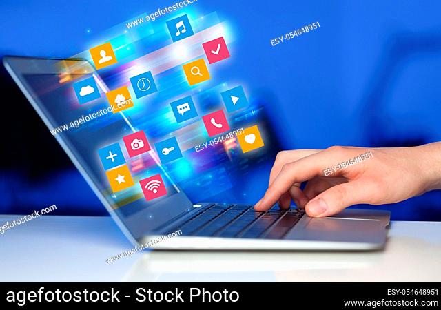 Hand using laptop with colorful fast moving application icons and symbols concept