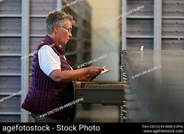 PRODUCTION - 11 July 2023, Hesse, Bad Arolsen: Nicole Dominicus, Head of the Archive Technology Department, stands at a cabinet with ""prisoner personnel...