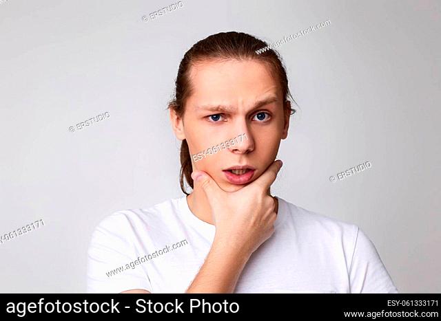 young handsome man touch his chin by hand thinking isolated on gray background