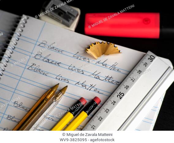 Black Lives Matter slogan written on a school calligraphy notebook, next to him rubber, pencil, pencil sharpener, pen and marker