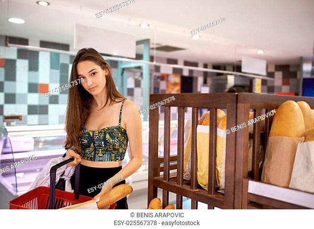 young woman shopping for fruits and vegetables in produce department of a grocery store supermarket