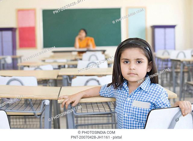 Portrait of a schoolgirl with her teacher sitting in the background