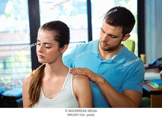 Physiotherapist massaging shoulder of a female patient
