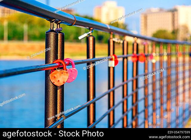 Colorful metal locks hanging on black railings in the sunrise light