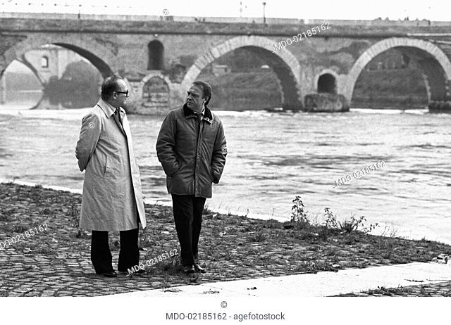 Italian writer and director Alberto Bevilacqua walking with Italian director and scenarist Pasquale Festa Campanile at Ponte Milvio. Rome, 1984