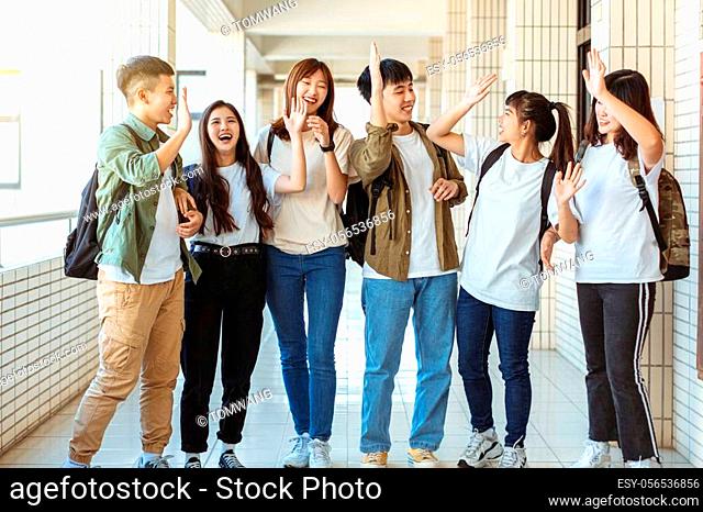 Group of happy students walking along the corridor at college