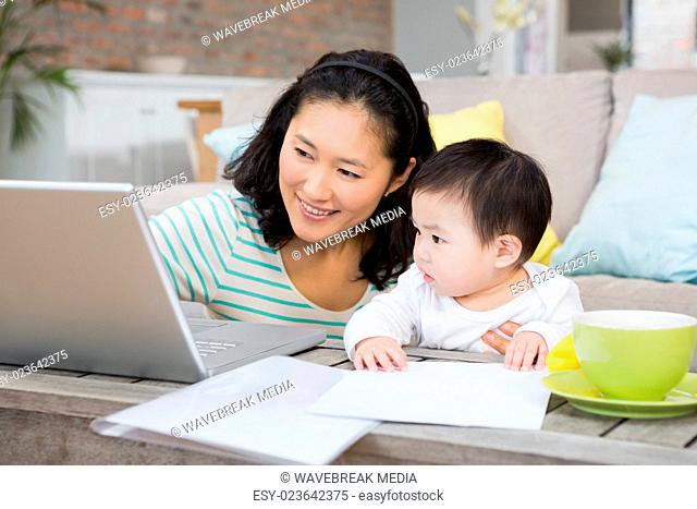 Happy mother with baby daughter using laptop