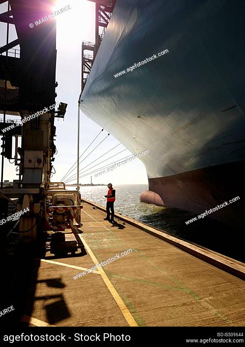 Dock worker beside cargo ship at Port of Felixstowe, England