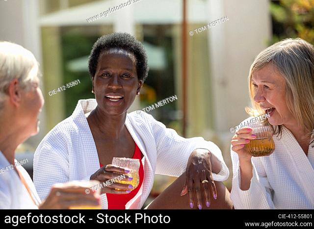 Happy senior women friends enjoying cocktails on sunny patio
