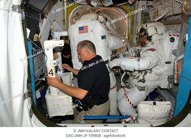 Astronaut Dave Wolf assists astronaut Tom Marshburn with some final touches on his extravehicular mobility unit spacesuit in the joint airlock