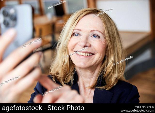 Smiling woman taking selfie through smart phone at home