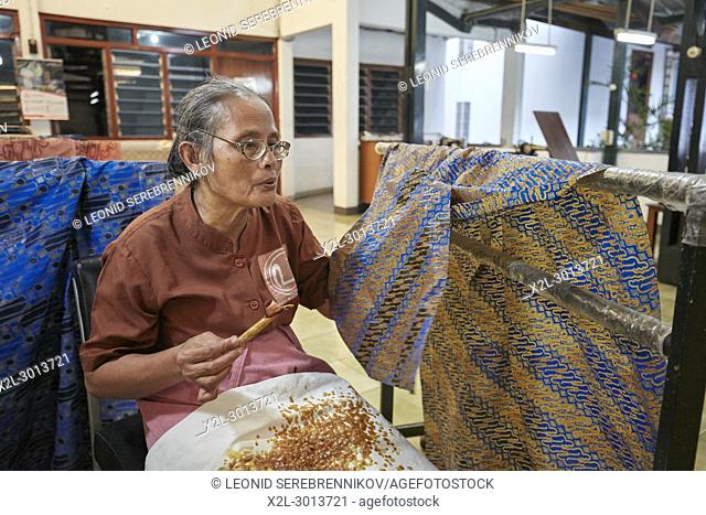Craftswoman applying hot wax-resist dyeing on batik with a canting (spouted tool). Batik Winotosastro shop, Yogyakarta, Java, Indonesia