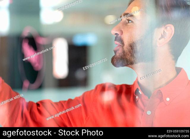 Portrait of caucasian businessman standing and making notes on glass wall