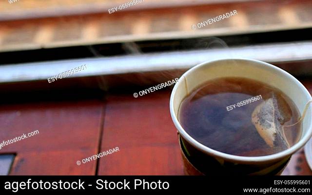 hot tea in a plastic container is enjoyed in a railroad car, against a background of blurry and unfocused outdoor scenes
