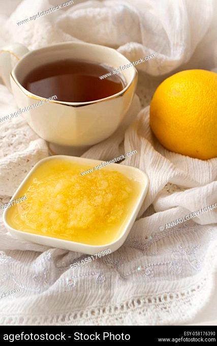 Healthy bowl of pure honey with honey dipper and lemon fruit and puree on vintage white background. Vertical image