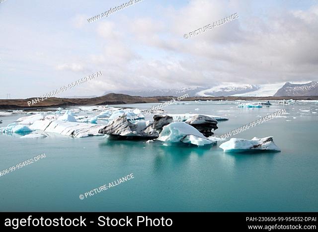 FILED - 12 April 2023, Iceland, Jökulsarlon: Icebergs float in Iceland's glacial lake Jökulsarlon, while a spur of the Vatnasjökull glacier can be seen in the...