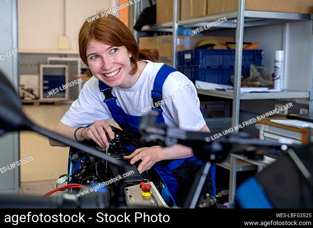 Smiling female technician looking away while working at workshop