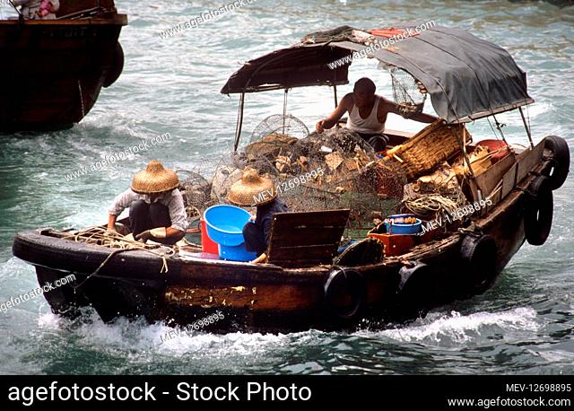 A fishing boat returns to Aberdeen Harbour, SW Hong Kong. The boat is loaded with nets and the crew prepare the mooring lines
