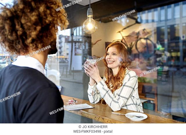 Man looking at smiling young woman in a cafe