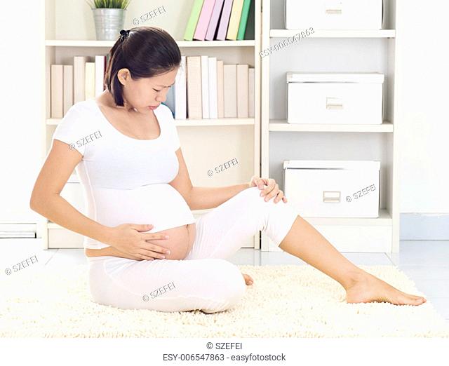 Pregnant Asian Woman at home with cramp leg. Woman health concept