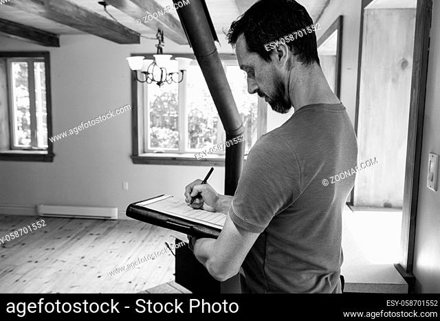 A monochrome and side profile view of a man carrying out a professional environmental air and moisture assessment inside a domestic building with copy space