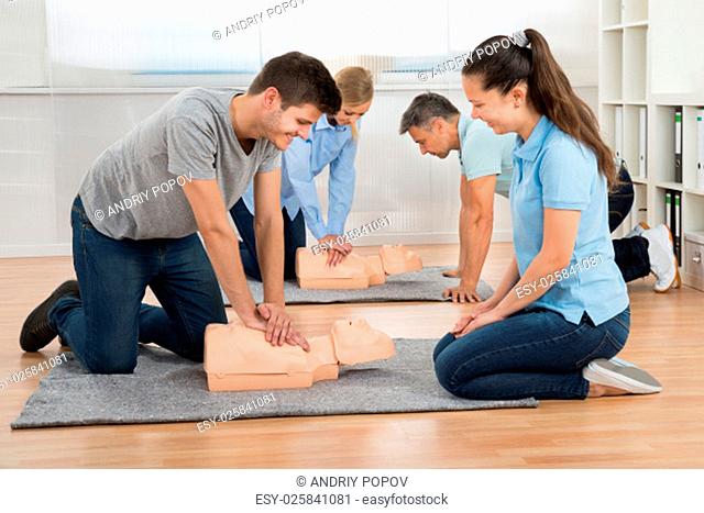Group Of Students Learning Cpr On Dummy In Class
