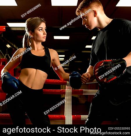 Sexy girl posing in boxing gloves and her boyfriend shot in boxing ring