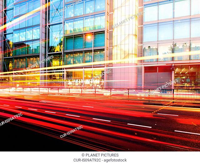 Traffic light trails and office building at dusk, London, UK