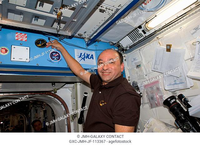 Astronaut Mark Polansky, STS-127 commander, places the STS-127 patch above a hatch in the Kibo laboratory, which adds to the growing collection of insignias...