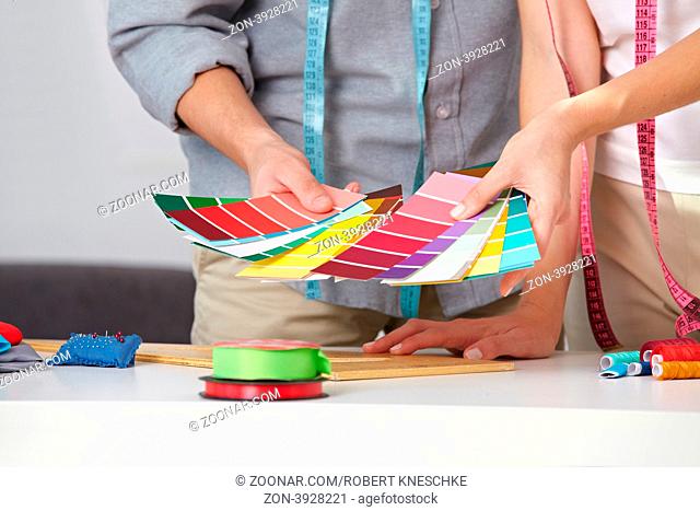 Zwei Modedesigner mit bunten Farbfächern in ihren Händen