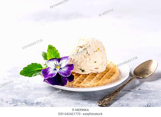 Vanilla ice cream scoop with edible flowers pansy. Summer food concept with copy space