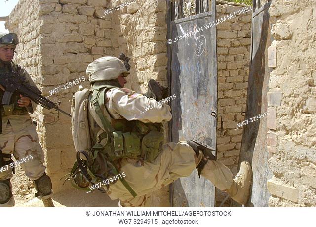 IRAQ Samarra -- 01 Oct 2004 -- A US Army soldier kicks in the front gate of a courtyard as they look for illegal weapons in house-to-house searches during...