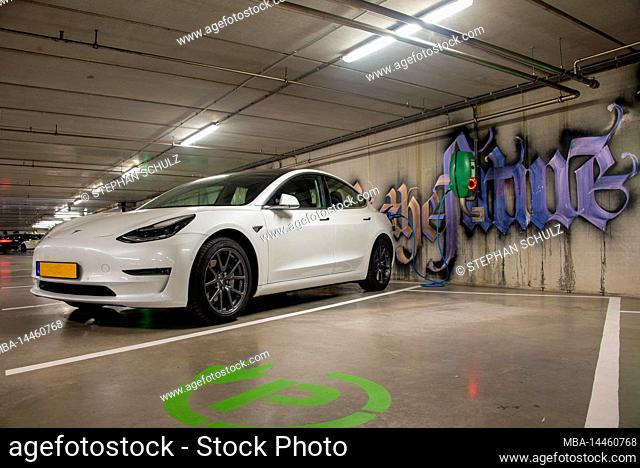 Tesla standing at electric charging station, underground car park, Amsterdam, Netherlands